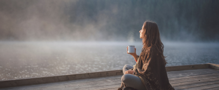 Mulher contemplando um lago em um momento de tranquilidade e equilíbrio emocional, representando formas naturais de aliviar a ansiedade.